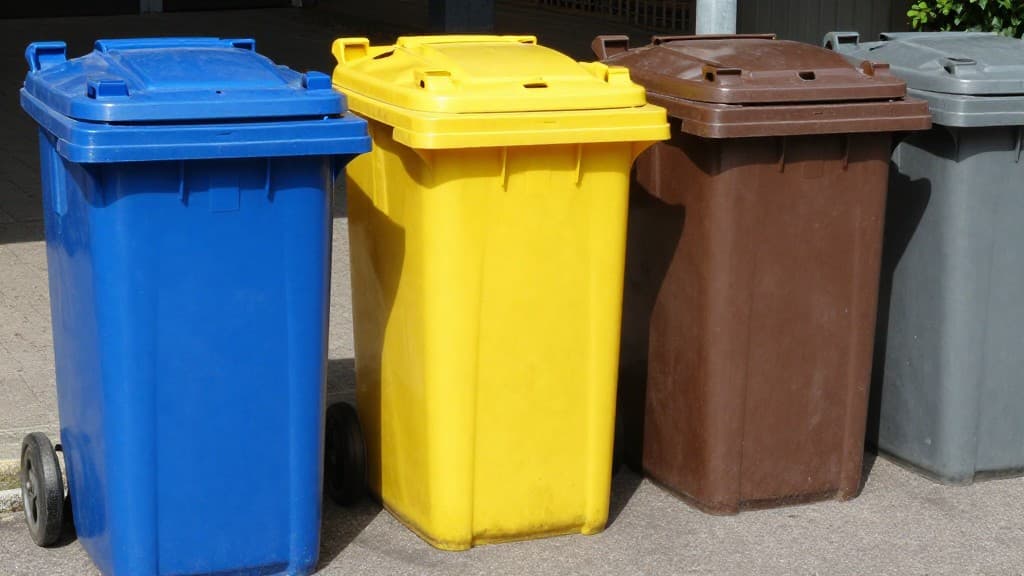 Farblich gekennzeichnete Recycling-Tonnen für verschiedene Abfallarten: Blau für Papier, Gelb für Verpackungen, Braun für Bioabfall und Grau für Restmüll